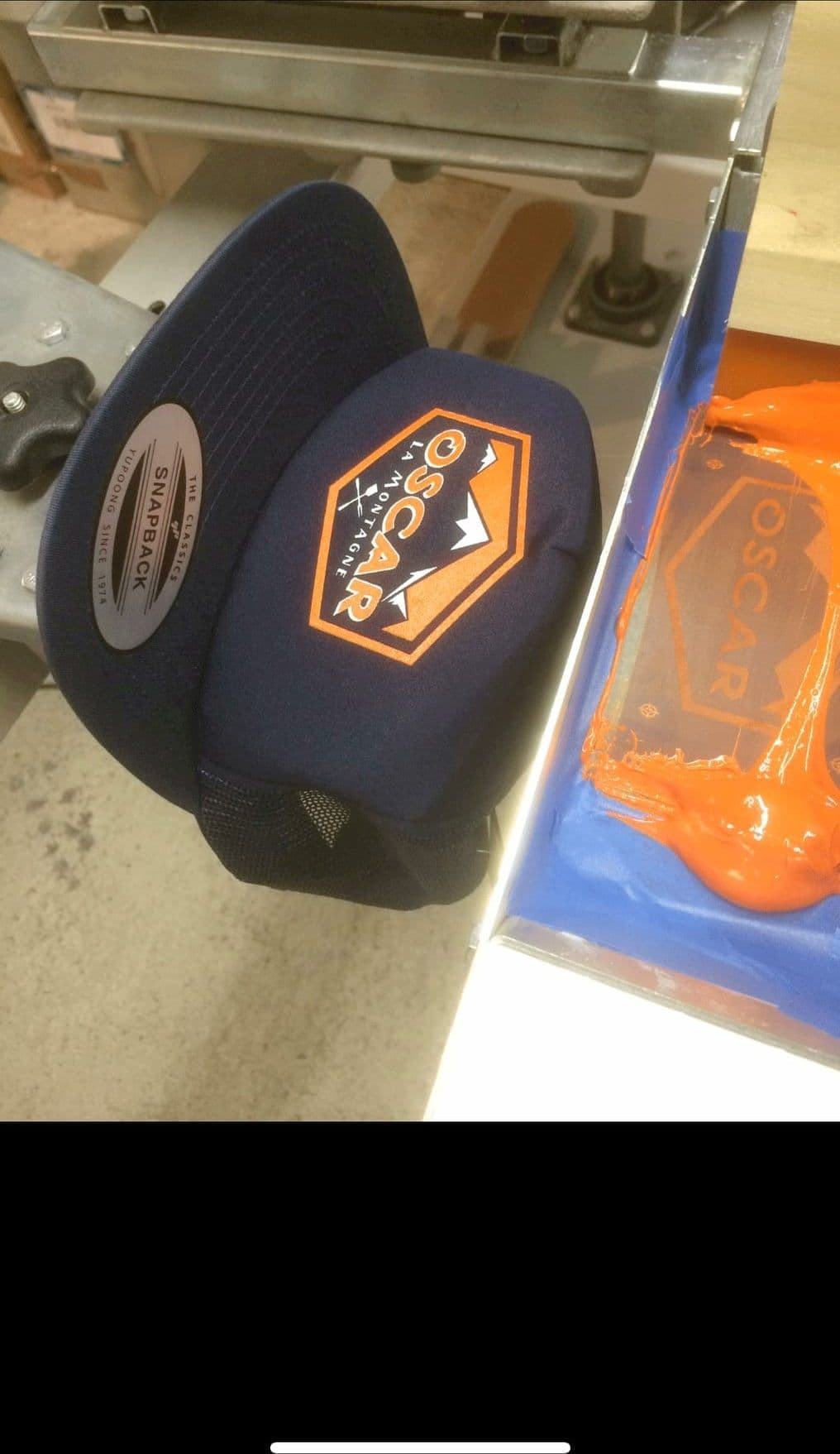Casquettes bleu marine à écusson orange, en sortie de broderie
