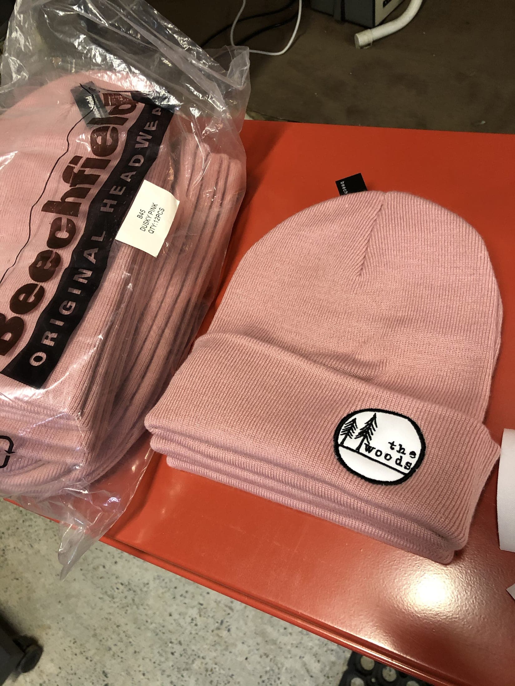 Bonnet rose à revers, écusson rond cousu, posé sur son conditionnement